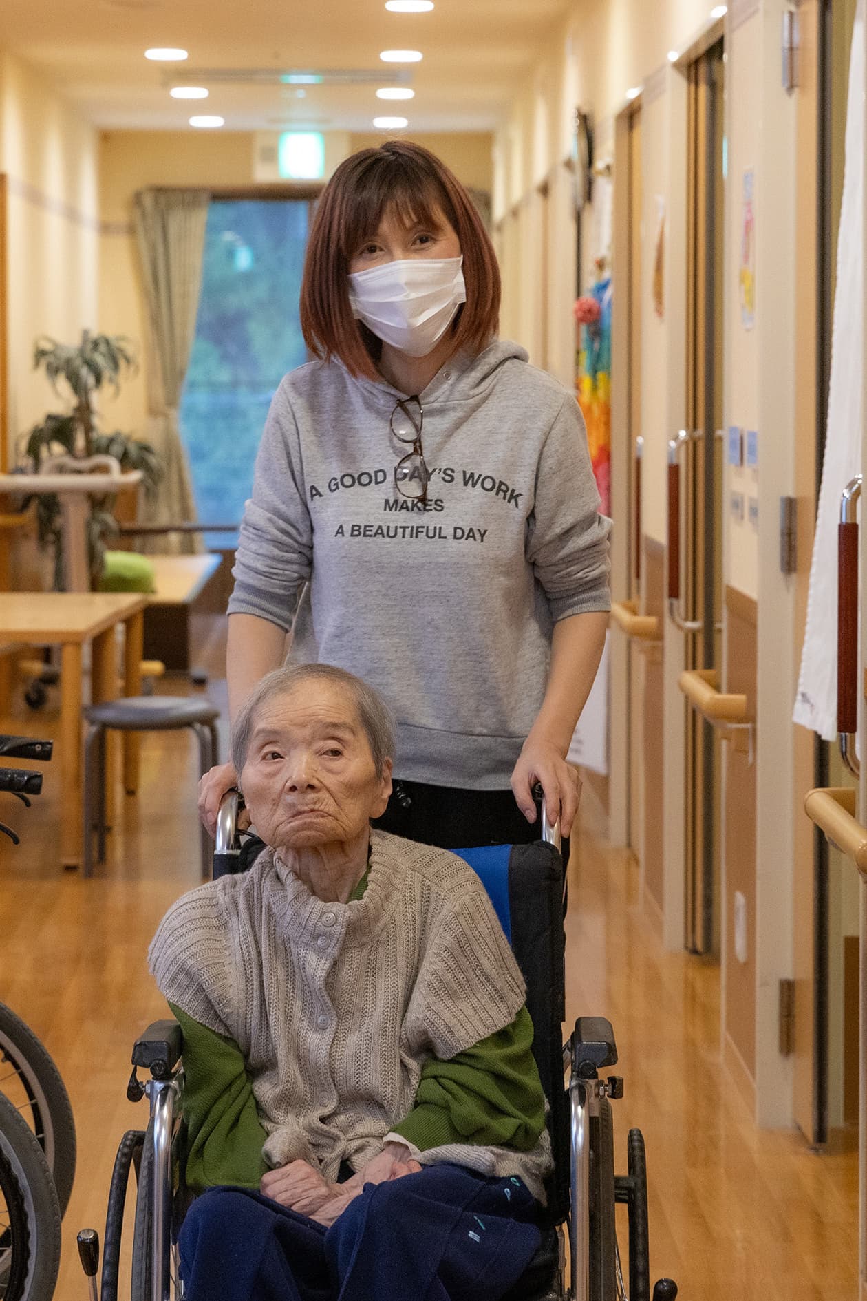 スタッフが高齢者を車椅子で介助している廊下での生活風景